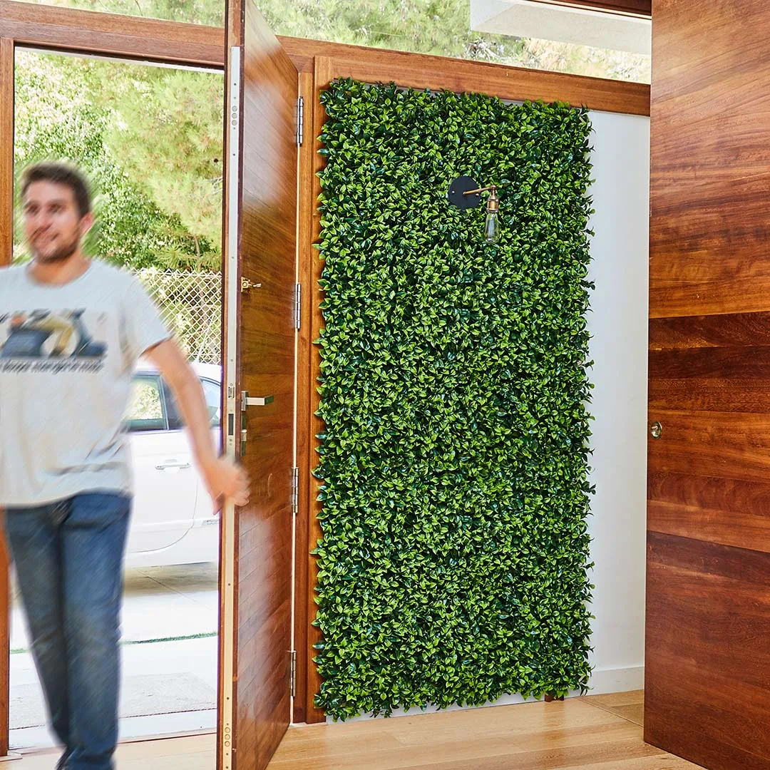 20010000004_1-142.jpg Varias losetas del Jardín Vertical Boj Balear instaladas, cubriendo una pared completa en el interior de una casa moderna con puertas de madera.